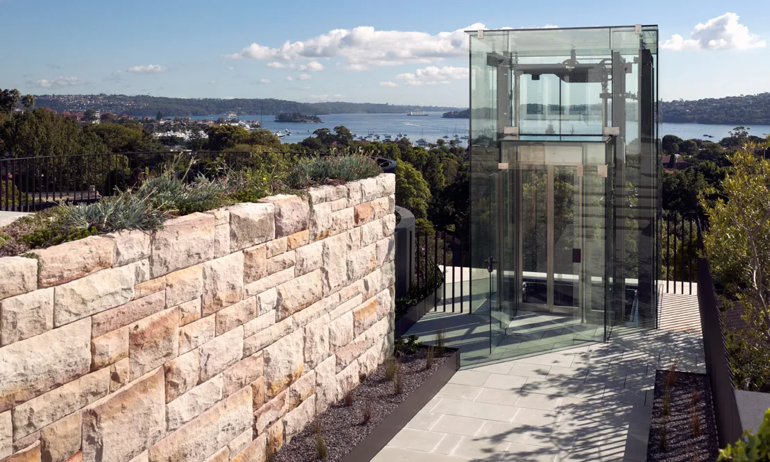 Sandstone wall and glass lift on a steep harbourside site, Bellevue Hill